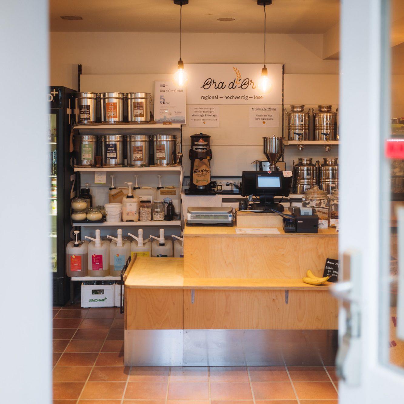 Ora d'Oro Eingangstür mit Blick auf den Kassenbereich. Hereinspaziert. Die Eingangstür ist geöffnet. Man sieht den Kassenbereich.